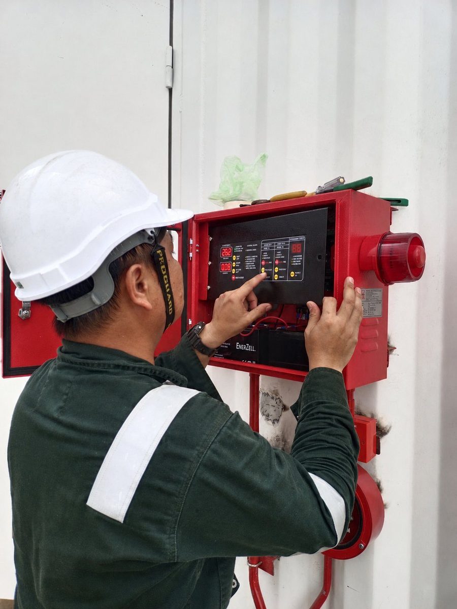 Technician testing a fire suppression control panel during commissioning work