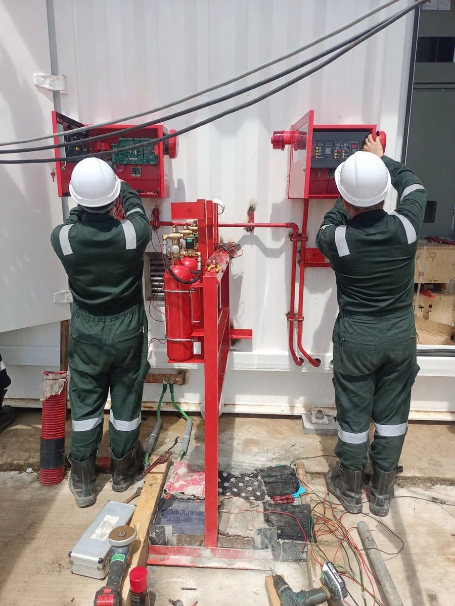 Technicians carrying out installation work on fire suppression panels and pipework