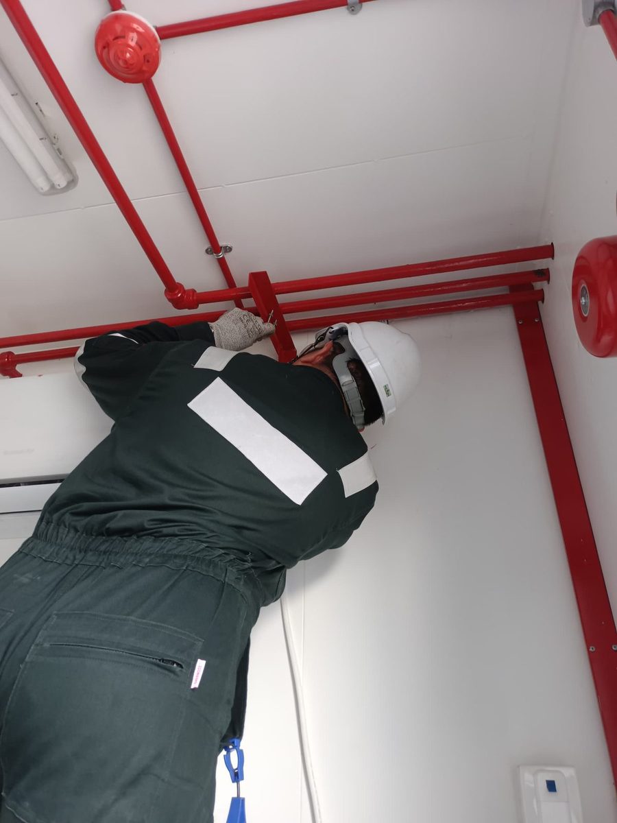 Technician carrying out installation work on red fire suppression pipework